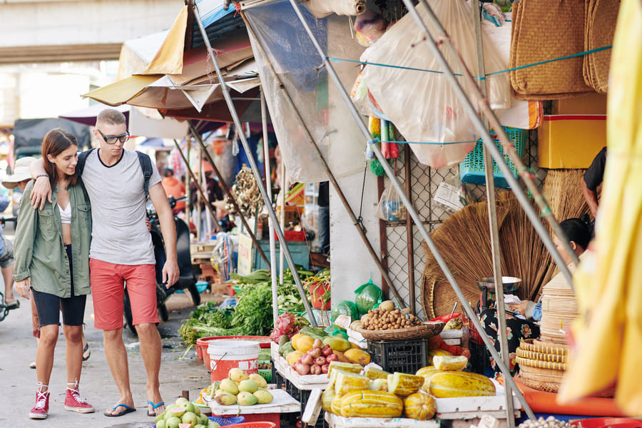 Pareja de viajeros explorando un mercado tradicional de frutas en China
